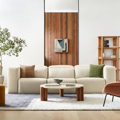 a living room with white furniture and wood paneling on the walls, along with a rug