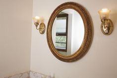 a bathroom with a mirror and two lights on the wall, next to a window