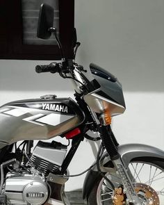 a silver and black yamaha motorcycle parked in front of a white wall with the words yamaha on it