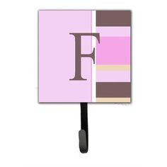 the letter f is displayed on a pink and brown striped wall mounted hook with a black handle