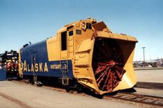 a yellow and blue train engine sitting on the tracks next to another train with it's front end open