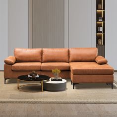 a brown leather couch sitting on top of a wooden floor next to a coffee table