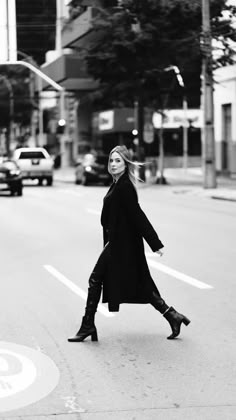 a woman walking down the street in black and white