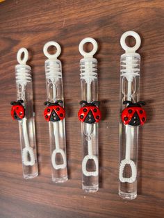 four little ladybug clips in clear plastic holders on a wooden table with scissors