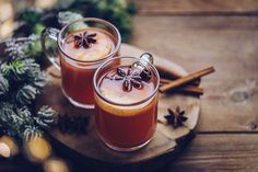 two mugs of hot mulled drink with cinnamon and star anise on the side