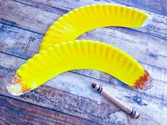 two banana shaped paper plates sitting on top of a wooden table next to a pencil