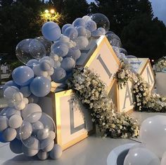 an outdoor event with balloons and flowers on the ground, in front of a house