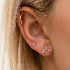 a close up of a person wearing an ear cuff with two small stars on it