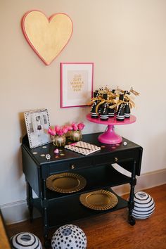 a black table with pink and white decorations on it next to a heart shaped wall