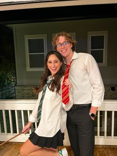 a man and woman posing for a photo in front of a house with their dog