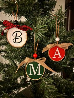 three ornaments hanging from a christmas tree decorated with monogrammed letters and bows on them