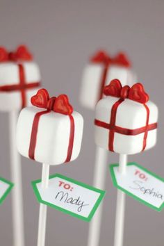 six white lollipops wrapped in red and green paper with presents on them