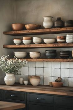 bowls and plates are arranged on wooden shelves above the counter top, along with flowers in vases