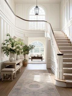 an elegant entryway with stairs and vases filled with flowers on either side of the staircase