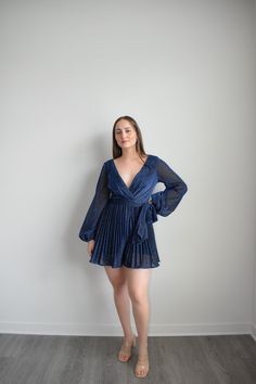 Navy Dress Romper with sparkling belt and long sleeves to dazzle at any formal event. Featuring an adjustable belt and a plunging v-neckline, you can elevate your look with sky-high heels or simply make it a more relaxed ensemble for at-home soirées. Crafted from a lightweight Polyester, this Navy Dress Romper is the epitome of grace and sophistication. Size guide: The First Model is 5'6" and wearing size Small. The Second model is wearing a size small Elegant V-neck Belted Dress For Evening, Elegant Belted Mini Dress For Party, Glamorous Long Sleeve V-neck Party Dress, Party Dresses With Belted Mini Length, Glamorous Belted Dresses For Date Night, Elegant V-neck Belted Mini Dress, Glamorous Spring Evening V-neck Dress, Glamorous V-neck Evening Dress For Spring, Spring Party Mini Length Belted Dress