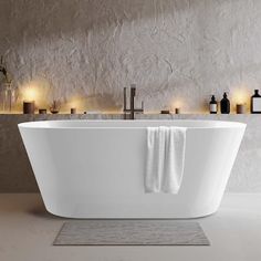 a large white bath tub sitting next to candles