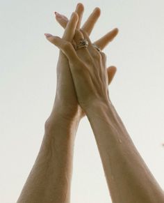 two hands reaching up into the sky with their fingers extended to reach for each other