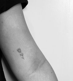 a black and white photo of a person's arm with a single flower tattoo on it