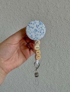 a hand holding a blue and white key chain