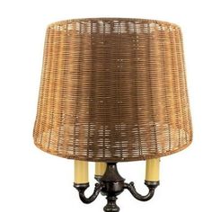 a wicker lamp with two yellow candles on the base and a brown shade over it