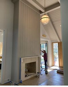 a man is painting the walls in a house that's being built with wood