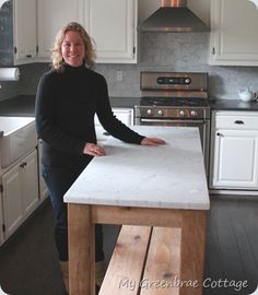 a woman standing at a kitchen island in front of a stove top oven and sink