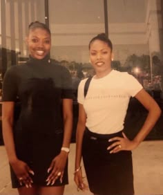 two women standing next to each other in front of a building