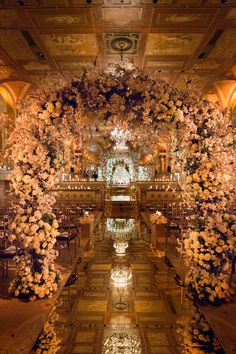 an elaborately decorated wedding ceremony hall with flowers on the ceiling and chandeliers hanging from the ceiling