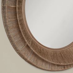 a round mirror that is made out of wicker and has a wooden frame around it