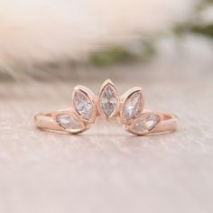 two diamond rings sitting on top of a white cloth covered table with flowers in the background