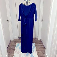 a blue dress is hanging on a white wall in front of a door with a hanger