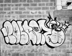 black and white photograph of graffiti on a brick wall