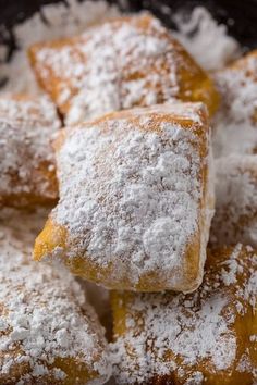 powdered sugar covered pastries sitting on top of each other in a black bowl