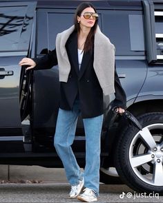 a woman is standing in front of a black suv with her hand on the door handle