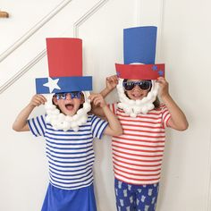 two children wearing patriotic hats and sunglasses standing next to each other in front of a door