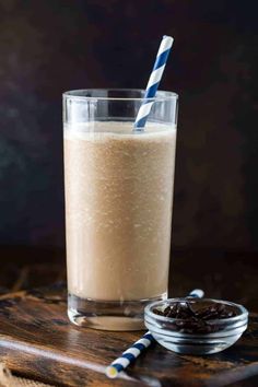 a glass filled with milk sitting on top of a table next to a bowl of raisins