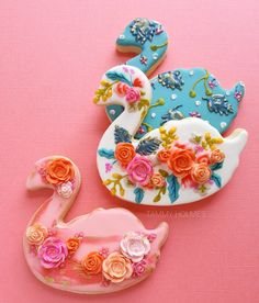 three decorated cookies sitting on top of a pink table next to each other with flowers