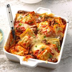 a casserole dish with meat and cheese in it next to a bowl of rice