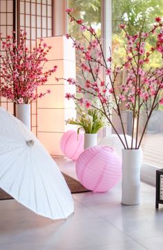 two vases with flowers and an umbrella in front of a window, on the floor