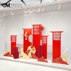 an exhibit with red and white paper cutouts on the wall, in front of a large display case