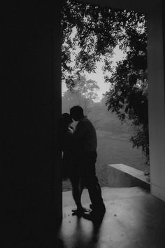 black and white photograph of two people standing in front of an open door with trees