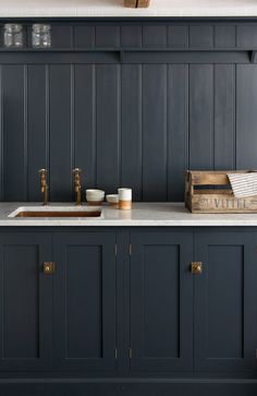 a kitchen with dark green cabinets and white counter tops, gold faucets and brass knobs