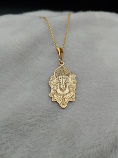 Celebrate spirituality and elegance with this exquisite Ganesha Necklace, crafted in 14K gold. This handmade piece features a delicate depiction of Lord Ganesh, making it a perfect religious charm necklace for those who cherish spiritual symbols. Its tiny and intricate design adds a subtle yet meaningful touch to any outfit, ideal for daily wear or special occasions. ⚜️ Package included: One Handmade Necklace ⚜️ Pendant Sizes: 14 / 16 / 18 / 20 / 22 / 24 / 26 / 28 / 30 mm ⚜️ Necklace Length: 14 Yellow Gold Necklaces For Navratri Celebration, 22k Gold Jewelry For Navratri Gift, 22k Gold Temple Jewelry Necklace As Gift, 22k Gold Temple Necklace With Intricate Design As Gift, Yellow Gold Jewelry For Puja Diwali, Yellow Gold Necklace With Intricate Design For Puja, Intricate Yellow Gold Necklace For Puja, Yellow Gold Jewelry For Diwali Puja, Gold Plated Temple Necklace As Festive Gift