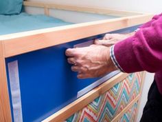 a person with their hand on the edge of a bed frame that is being made