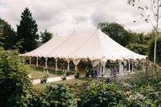 a large white tent set up in the middle of a field with flowers around it