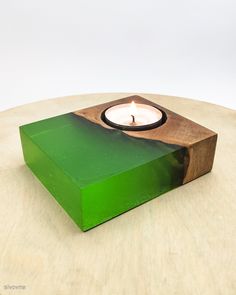 a green candle holder sitting on top of a wooden table