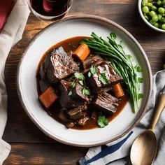 a bowl filled with meat and vegetables next to a glass of wine on top of a wooden table