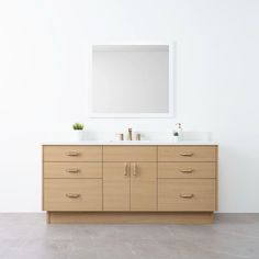 a bathroom vanity with two sinks and a large mirror above it, in front of a white wall