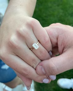 two people holding hands while standing in the grass with their wedding rings on top of each other