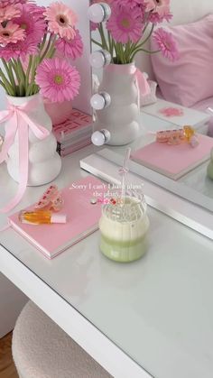 pink flowers in white vases sitting on a table next to books and other items